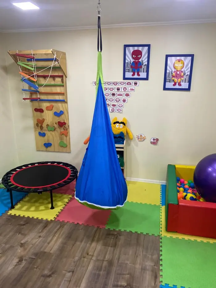 Sala de estimulación sensorial con columpio, cama elástica y muro de escalada