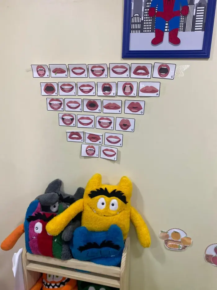 Pared con tarjetas fonoarticulatorias y peluches en sala de terapia infantil