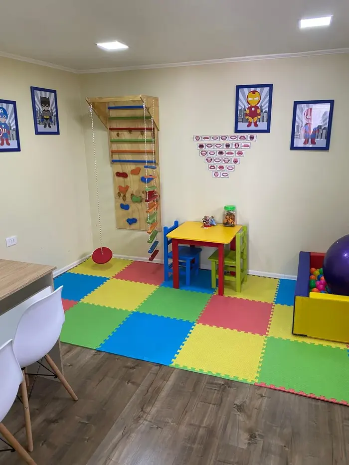 Sala de juegos y terapia ocupacional con muro de escalada, mesa infantil y piscina de pelotas